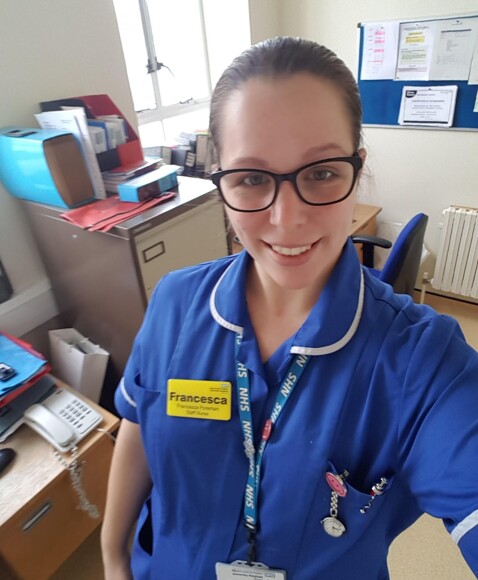 Francesca posing in her nurse uniform in an office at the hospital